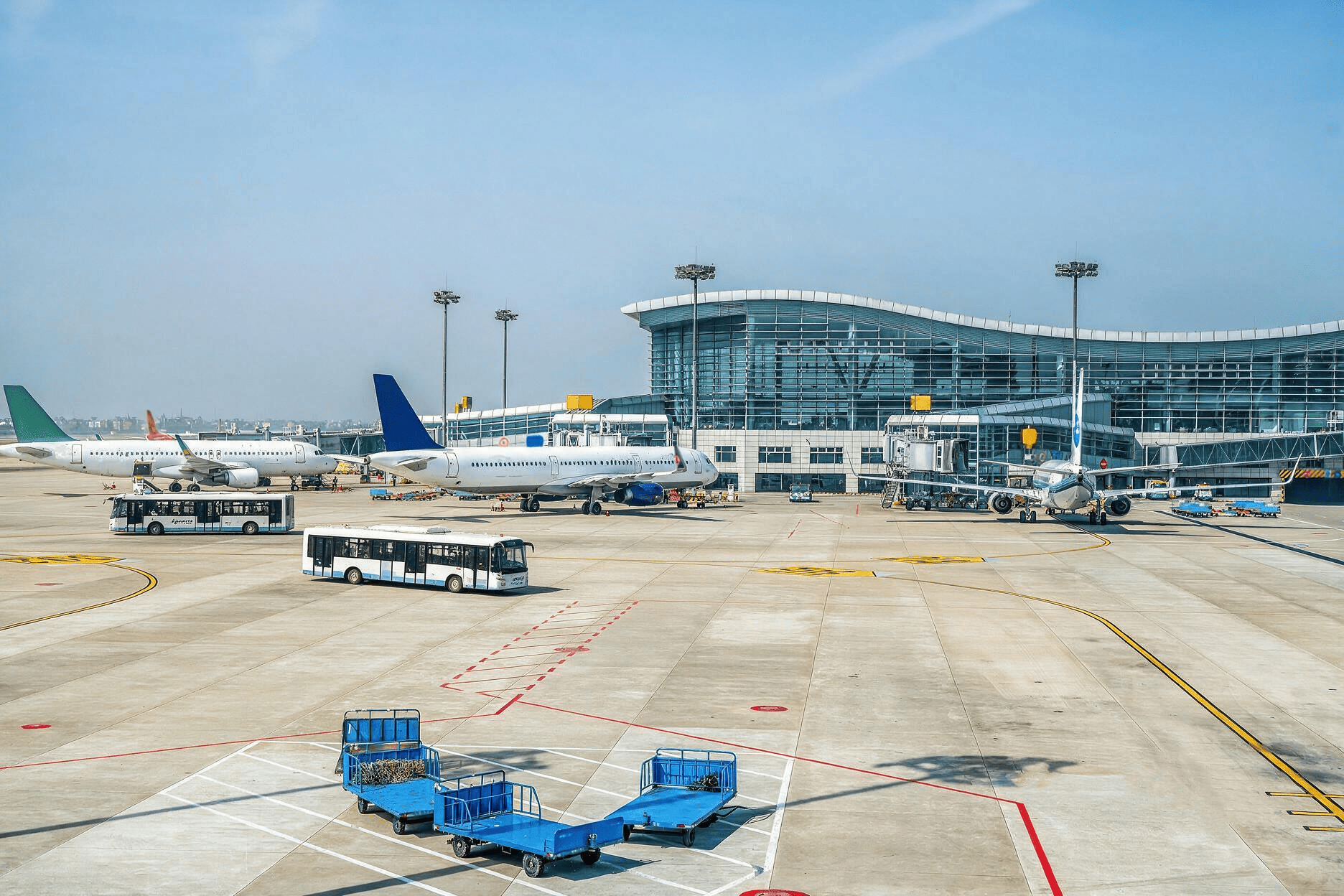 Aircraft and ground-service vehicles outside an airport terminal.
