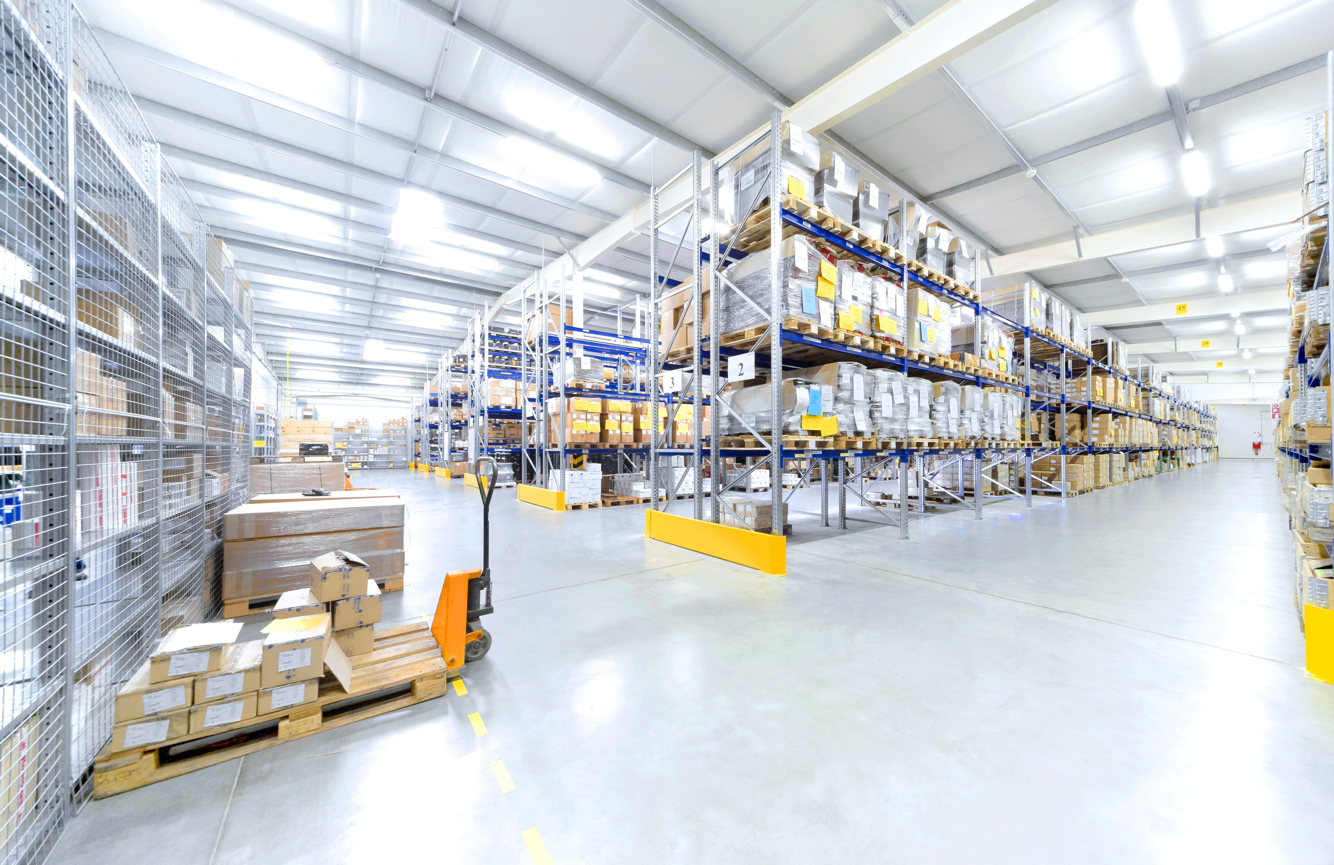 Warehouse aisle with shelves, pallets, and logistics equipment.